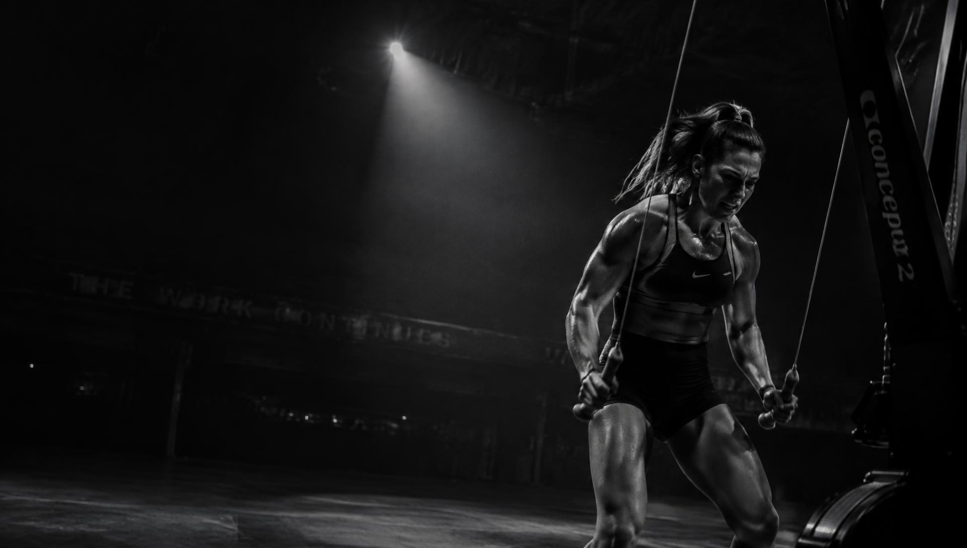 Athlete driving through a SkiErg pull under a single spotlight
